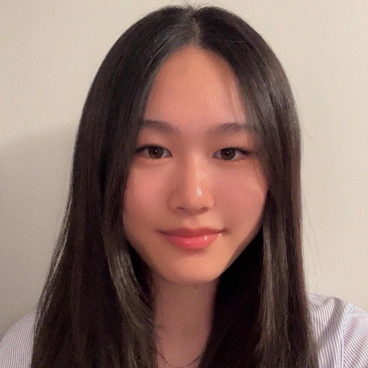 Close-up portrait of Chelsea with long dark hair, looking at the camera against a plain light background.