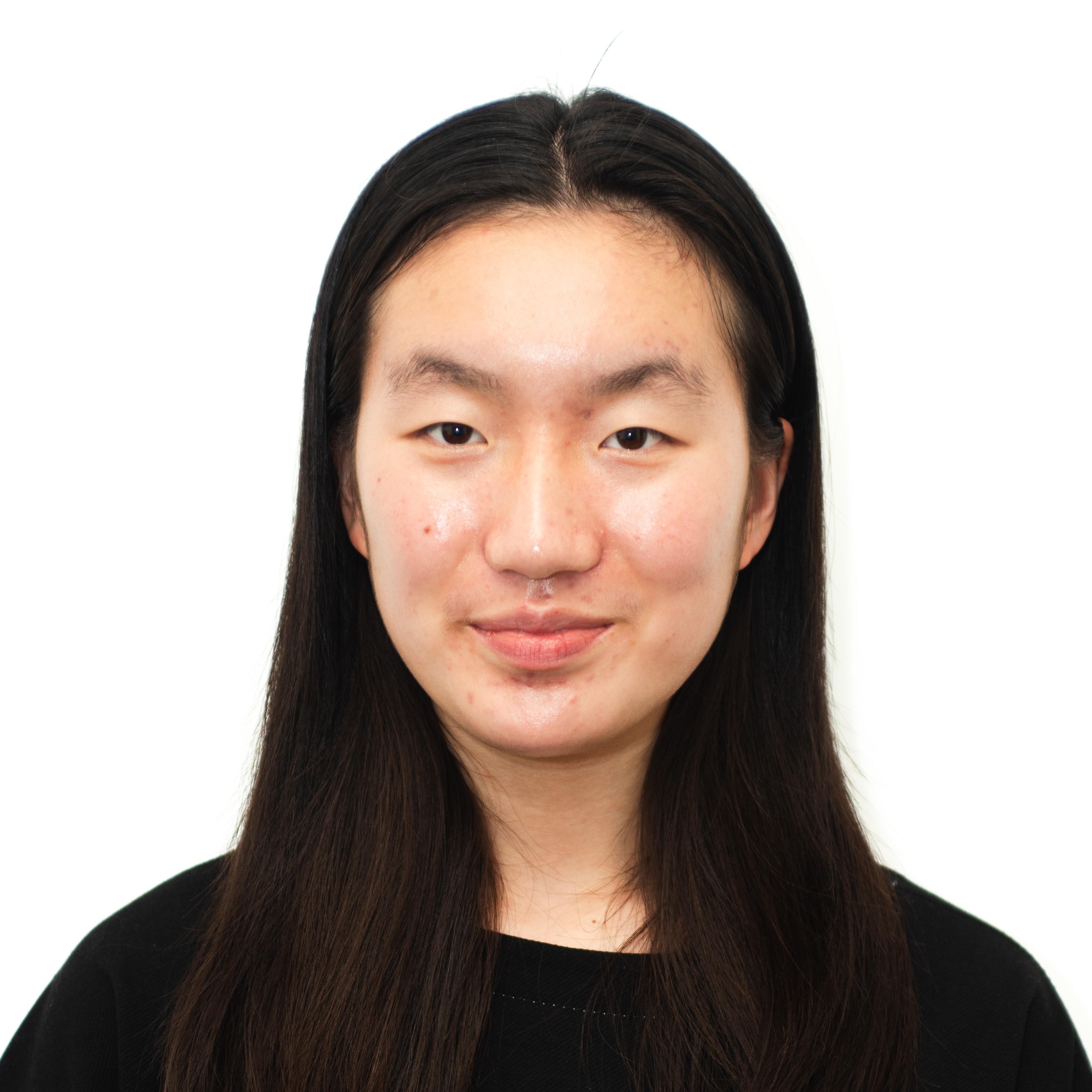Studio headshot of Elaina with long dark hair, facing forward and smiling slightly against a white background.