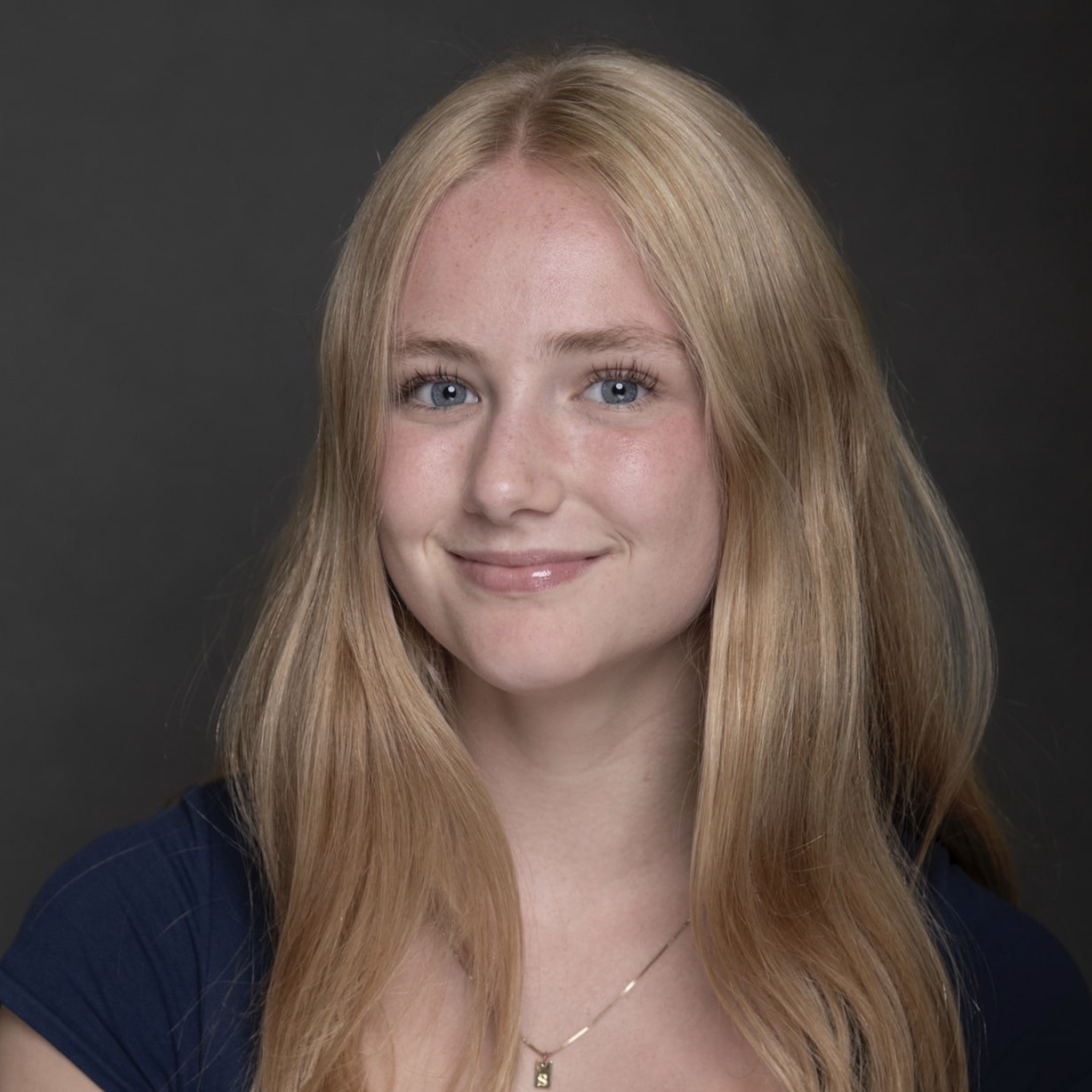 Studio headshot of Sidney with long blonde hair against a dark gray background.