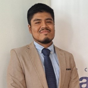 Headshot of Jorge Burmeo smiling in a tan suit with a dark blue tie